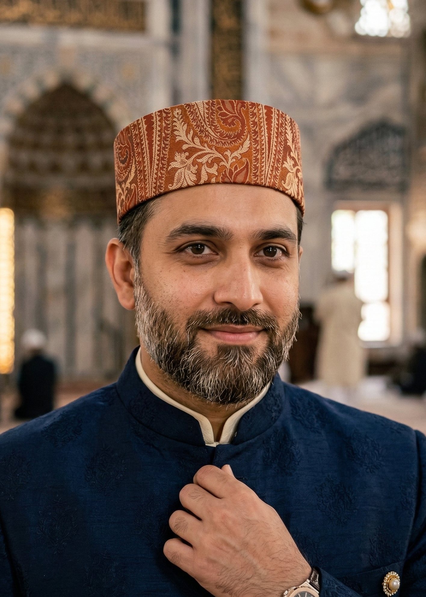 Man wearing a patterned cap and dark blue jacket in a mosque setting