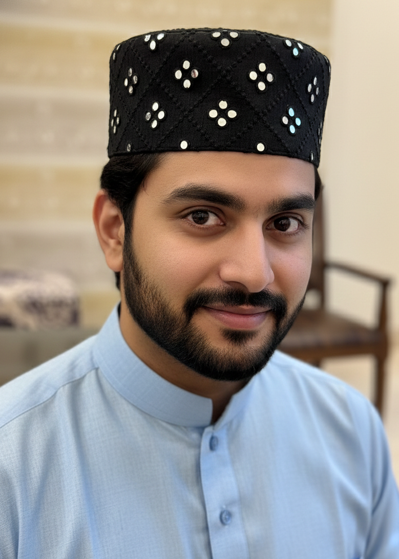 Man wearing a black cap with white patterns and a light blue shirt indoors.